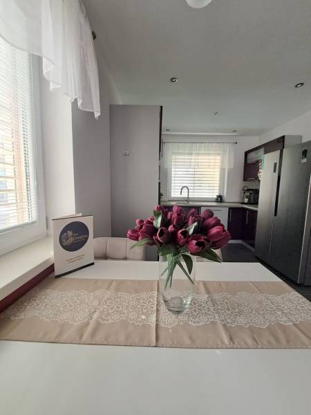 Konyha egy családi házban, tulipánokkal az asztalon és fehér függönyökkel.