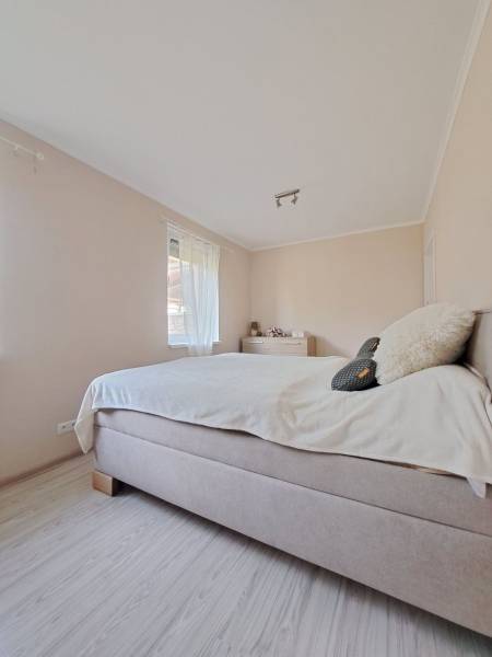 Világos hálószoba családi házban kényelmes ággyal és fa dekoros padlóval.