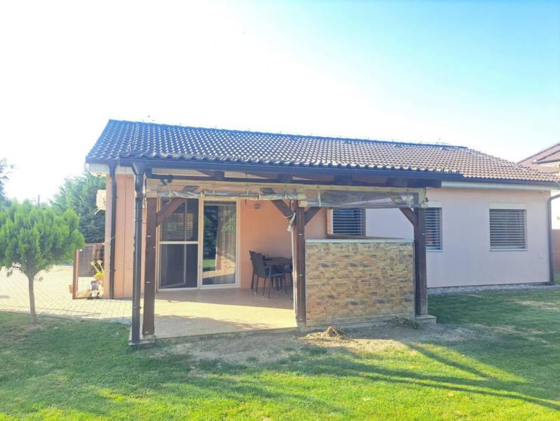 Családi ház Feketevárosban terasszal, kerttel és pergolával, zöld gyep veszi körül.