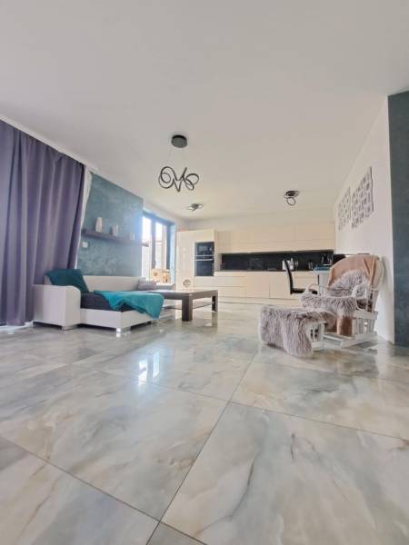 Nappali nagy ablakokkal és világos csempékkel egy családi házban.