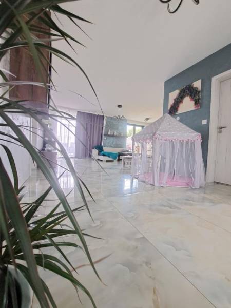 Családi ház belső tere gyerekeknek szánt sátorral a fényes padlón és növényekkel.