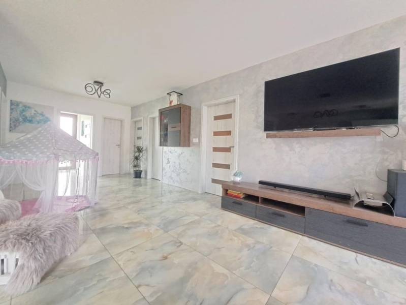 Nappali családi házban, falra szerelt televízióval, sátorral és kerámia padlóval.