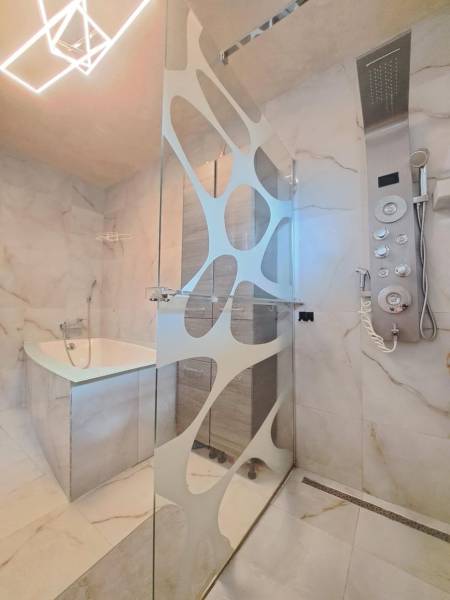 Fürdőszoba modern zuhanyzóval, káddal és dizájnos világítással egy családi házban.