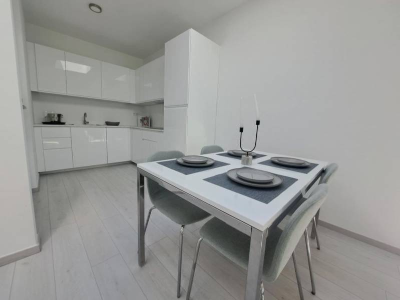 Étkező sarok egy kétszobás lakásban, konyhabútorral és fa dekoros padlóval.