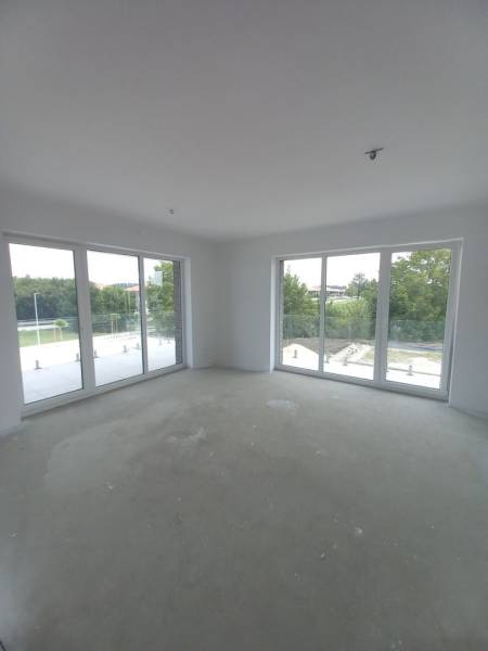 Nagy ablakok és természetes fény a kétszobás lakásban, kilátással a zöldre.