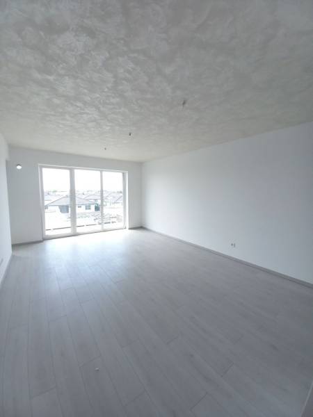 Világos szoba fa dekor padlóval és nagy ablakokkal egy kétszobás lakásban.