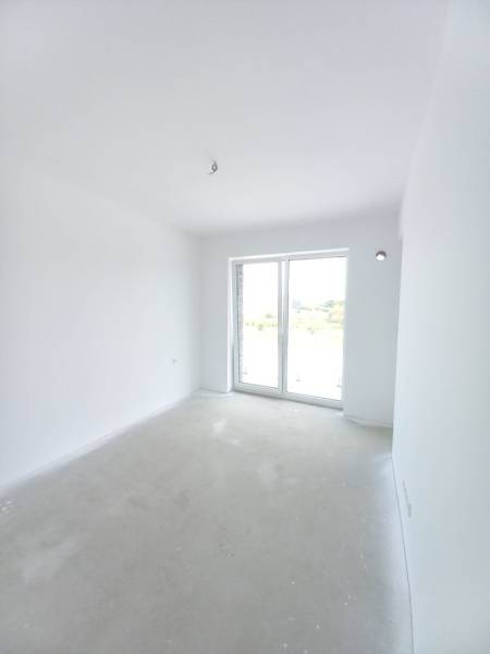 Világos szoba egy kétszobás lakásban nagy ablakkal és fehér falakkal.