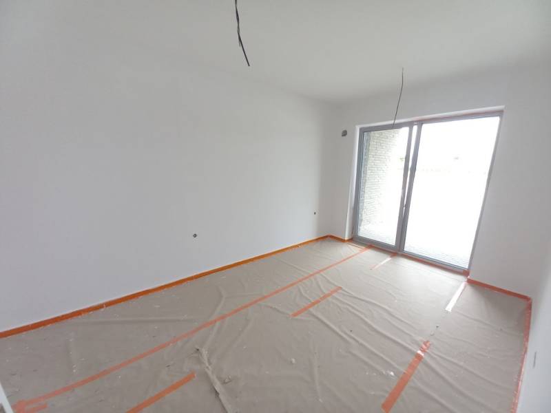 Kereskedelmi helyiségek nagy ablakkal, fehér festés, fa dekorációjú padló fóliával letakarva.