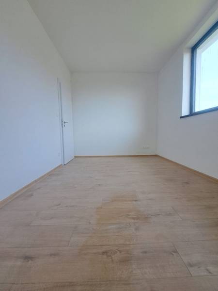 Családi ház belső tere világos szobával, fa dekorú padlóval, nagy ablakkal.