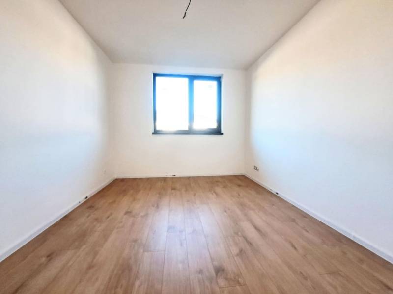 Kilátás egy fehér falú és fa dekor padlójú szobára egy családi házban.