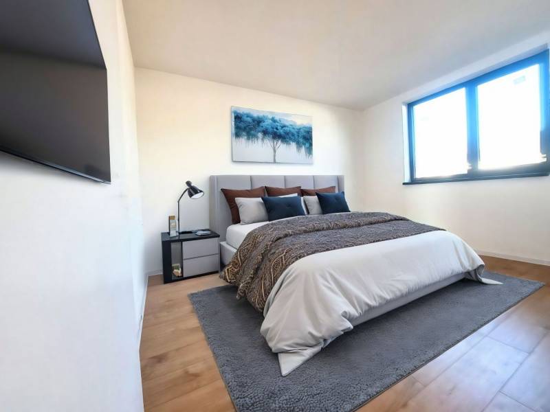 Hálószoba családi házban ággyal, képpel, TV-vel és fa dekorációjú padlóval.