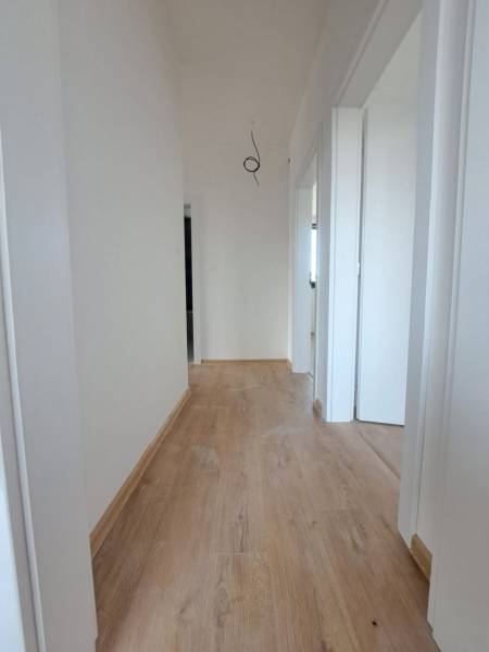 Folyosó fehér falakkal és fa dekorációval ellátott padlóval egy családi házban.