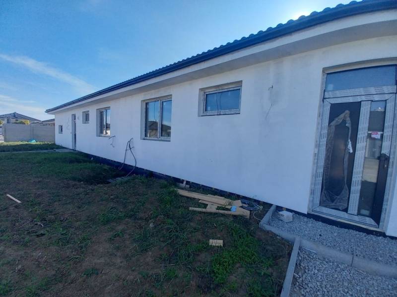 Családi ház Galántán fehér homlokzattal, nagy ablakokkal, építés alatt álló környezettel.