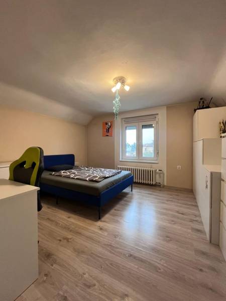 Hálószoba egy családi házban fa dekor padlóval, ággyal és íróasztallal.