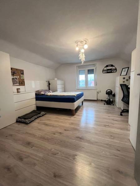 Hálószoba családi házban ággyal, fehér bútorokkal és fa dekorációjú padlóval.