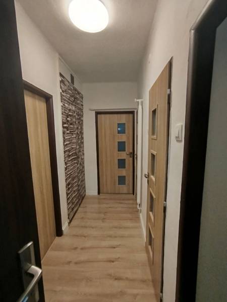 Folyosó világos padlóval és faajtókkal egy háromszobás lakásban.