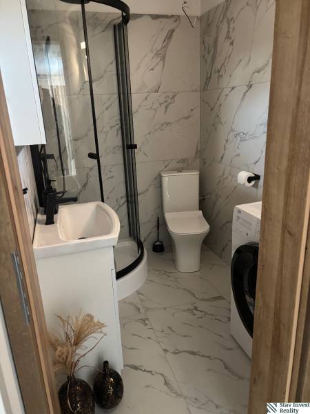 Fürdőszoba családi házban márványburkolattal, zuhanyzóval és mosógéppel.