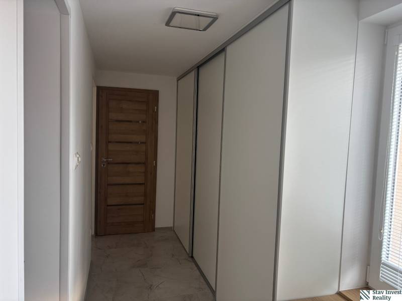 Folyosó egy családi házban tolóajtós szekrénnyel és faajtókkal.