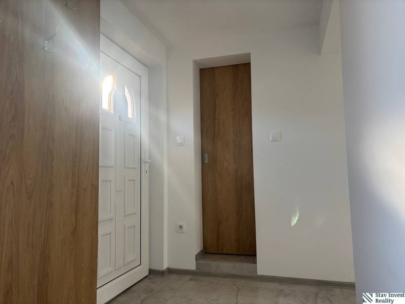 Családi ház belső tere fehér ajtókkal és fa dekorációjú padlóval.