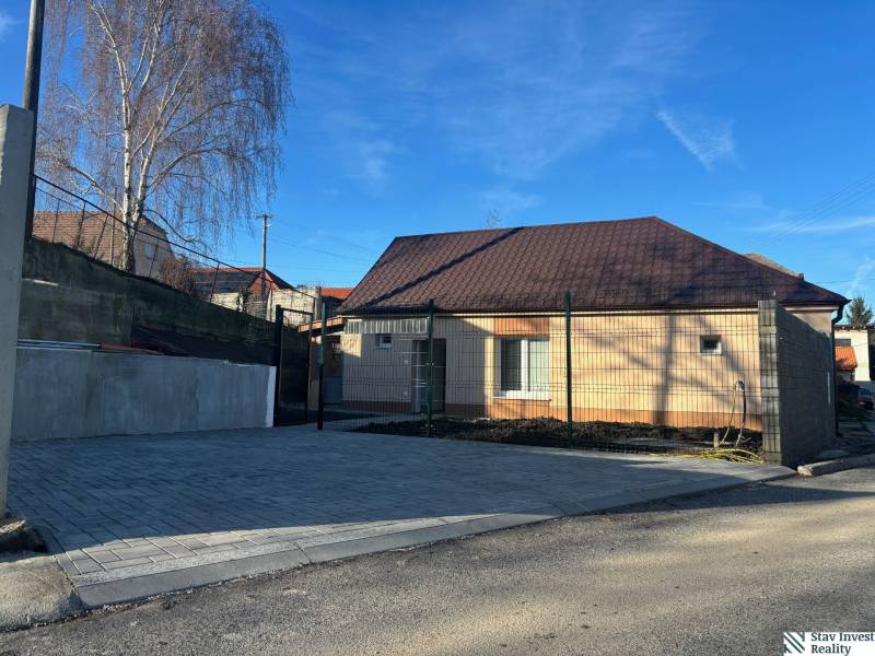 Családi ház Baráton barna tetővel, kövezett parkolóval és betonkerítéssel.