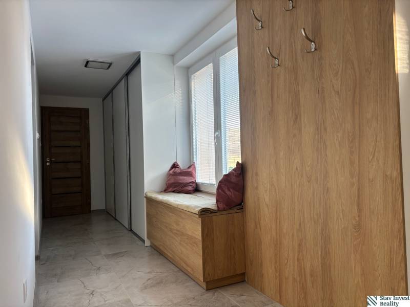 Folyosó családi házban fogasokkal és párnás üléssel, fa mintázatú padlóval.