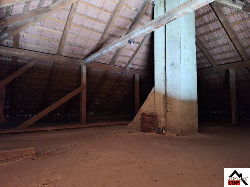 Családi ház tetőtere fa gerendákkal és kerámia tetőcseréppel.