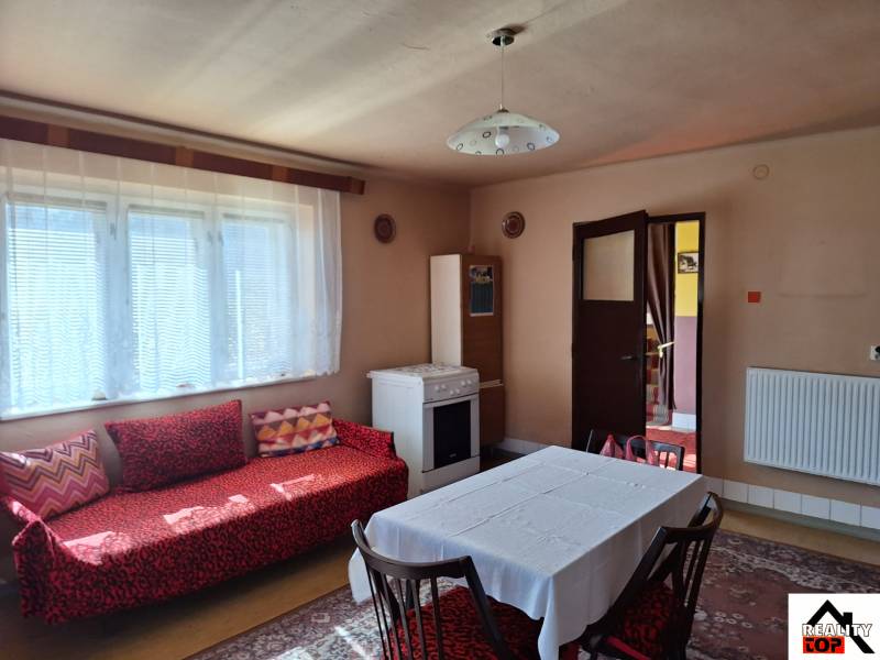 Családi ház belső tere kanapéval, étkezőasztallal és tűzhellyel.