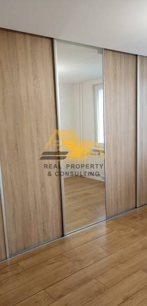 Beépített szekrény tükörrel és fa dekorációjú padlóval egy kétszobás lakásban.