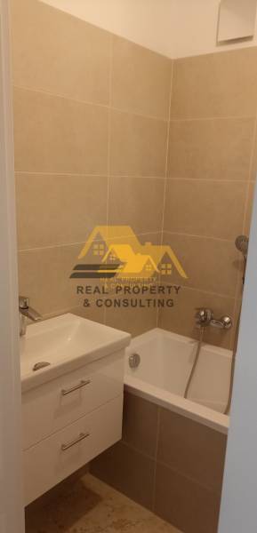 Fürdőszoba káddal és mosdóval egy kétszobás lakásban, bézs csempékkel.