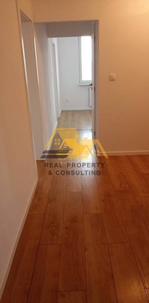 Folyosó fa dekor padlóval egy kétszobás lakásban, semleges falak.