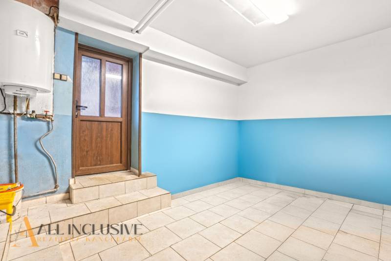 Családi ház belső tere kék falakkal és világos padlóval a faajtó mellett.