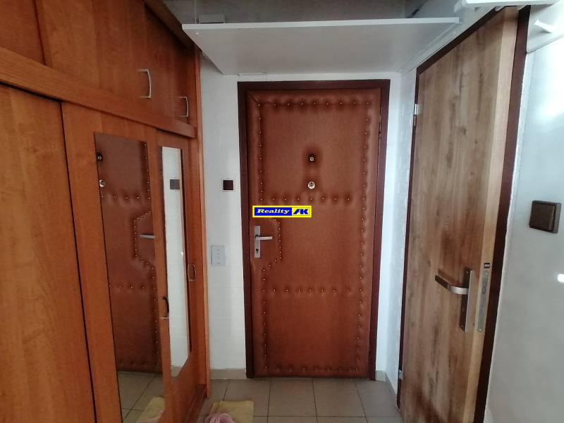 Az egyszobás lakás előszobája fa dekorral és praktikus tükörrel a szekrényen.