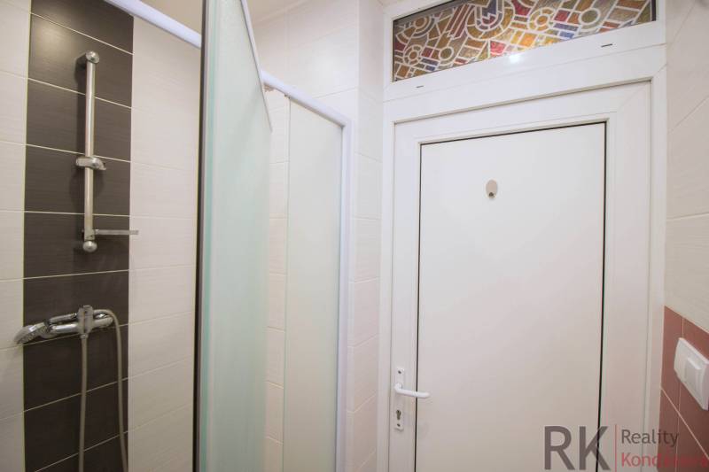 Fürdőszoba fehér és sötét csempék kombinációjával egy kétszobás lakásban.