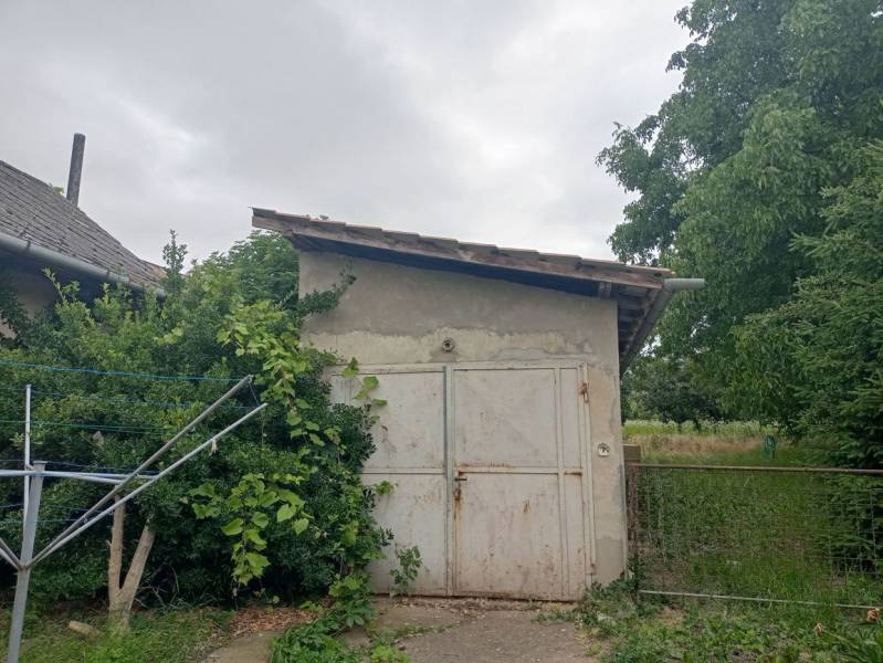 Családi ház Strekovban, kis fészerrel, zölddel és fákkal körülvéve.