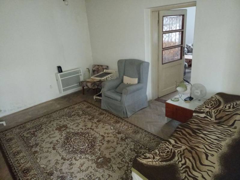 Szoba egy családi házban szőnyeggel, fotelekkel és ággyal.