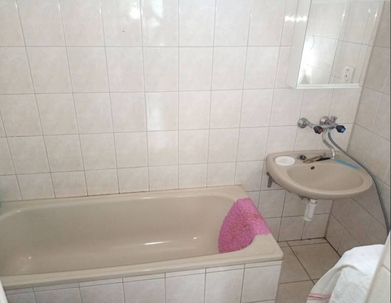 Fürdőszoba káddal és mosdóval családi házban, világos csempék és padlóburkolat.