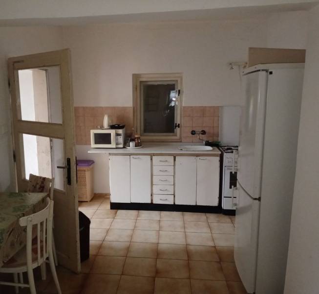 Konyha családi házban fehér szekrényekkel, mikrohullámú sütővel és hűtőszekrénnyel.