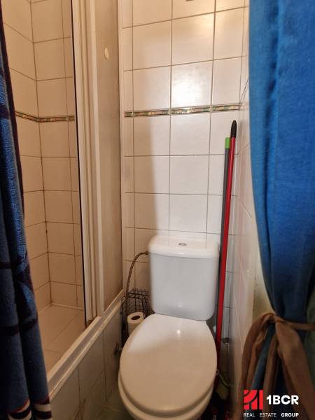 Fürdőszoba garzonlakásban WC-vel és zuhanyzóval, dekoratív csempével.