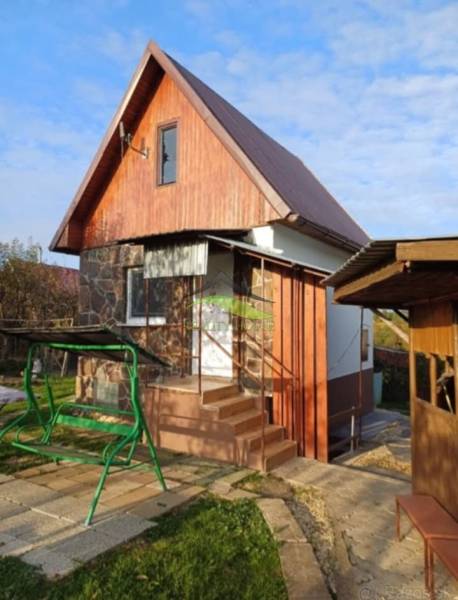 Pozdišovce-i faház fa burkolattal és hintával a kertben.