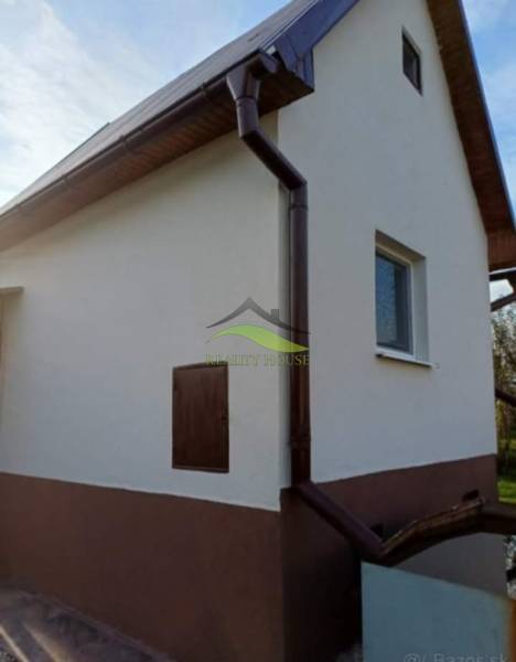 Pozdišovcei ház fehér homlokzattal és sötét ereszcsatorna-rendszerrel.