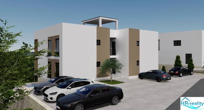 Nyaraló apartman Ciovo szigetén parkoló autókkal és környező zöldterülettel.