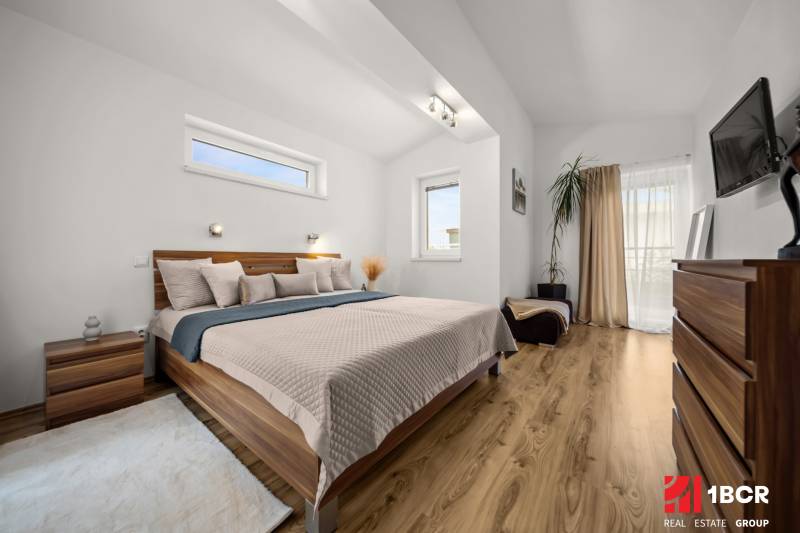 Hálószoba családi házban ággyal, dekoratív elemekkel és fa dekoros padlóval.