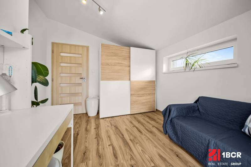 Szoba egy családi házban, fa dekoros padlóval, szekrénnyel és kanapéval.