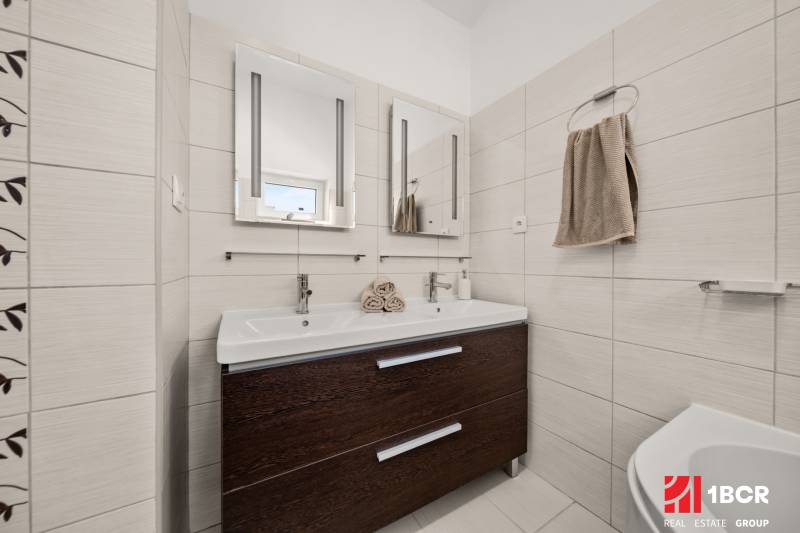 Fürdőszoba családi házban dupla mosdóval és sötét szekrénnyel.