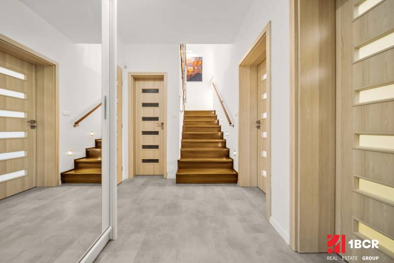 Családi ház előszobája fa mintázatú padlóval és lépcsővel.