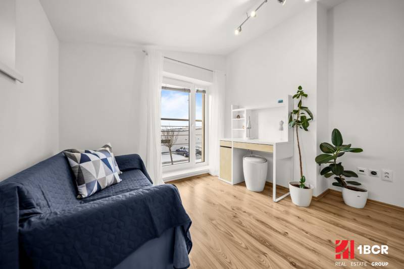 Szoba egy családi házban, fa mintázatú padlóval, kék kanapéval és íróasztallal.