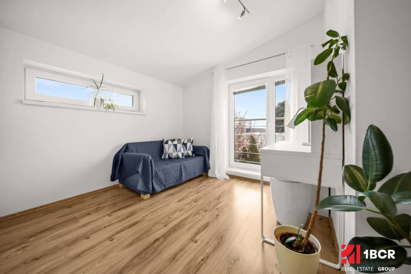 Szoba családi házban kanapéval, ablakokkal és fa dekorációjú padlóval.