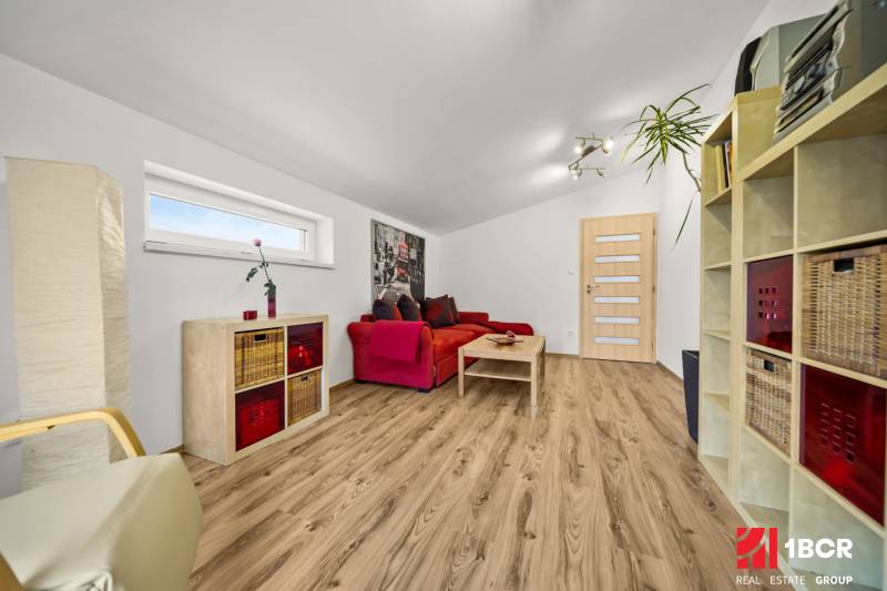 Nappali egy családi házban piros kanapéval és fa mintázatú padlóval.