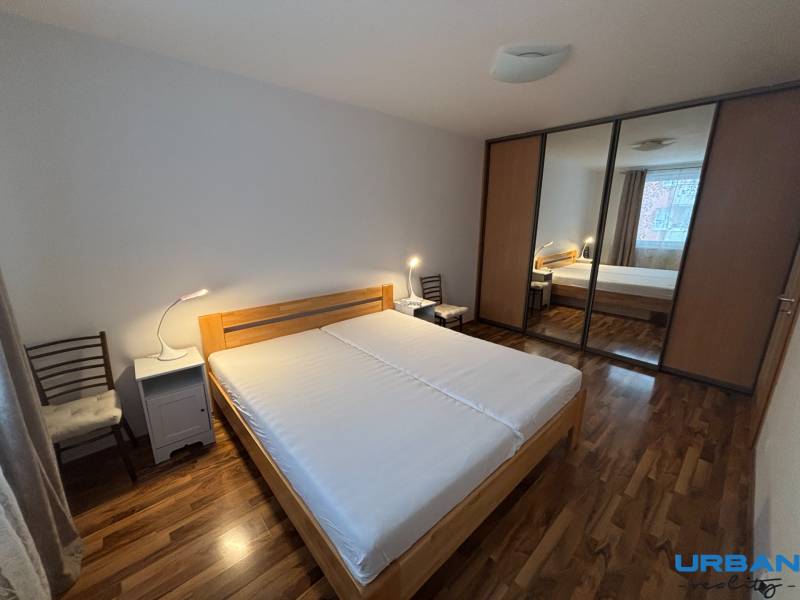 Hálószoba ággyal, tolóajtós szekrénnyel és fa dekoros padlóval.