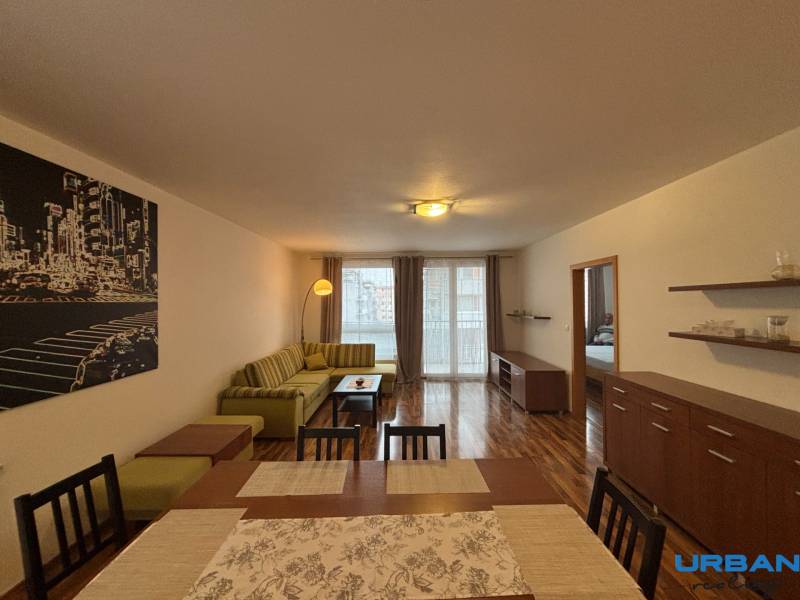 Nappali fa mintázatú padlóval, kanapéval és étkezőasztallal egy kétszobás lakásban.